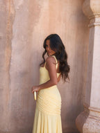 Vestido largo escultural con parte superior drapeada, color amarillo claro, vista lateral